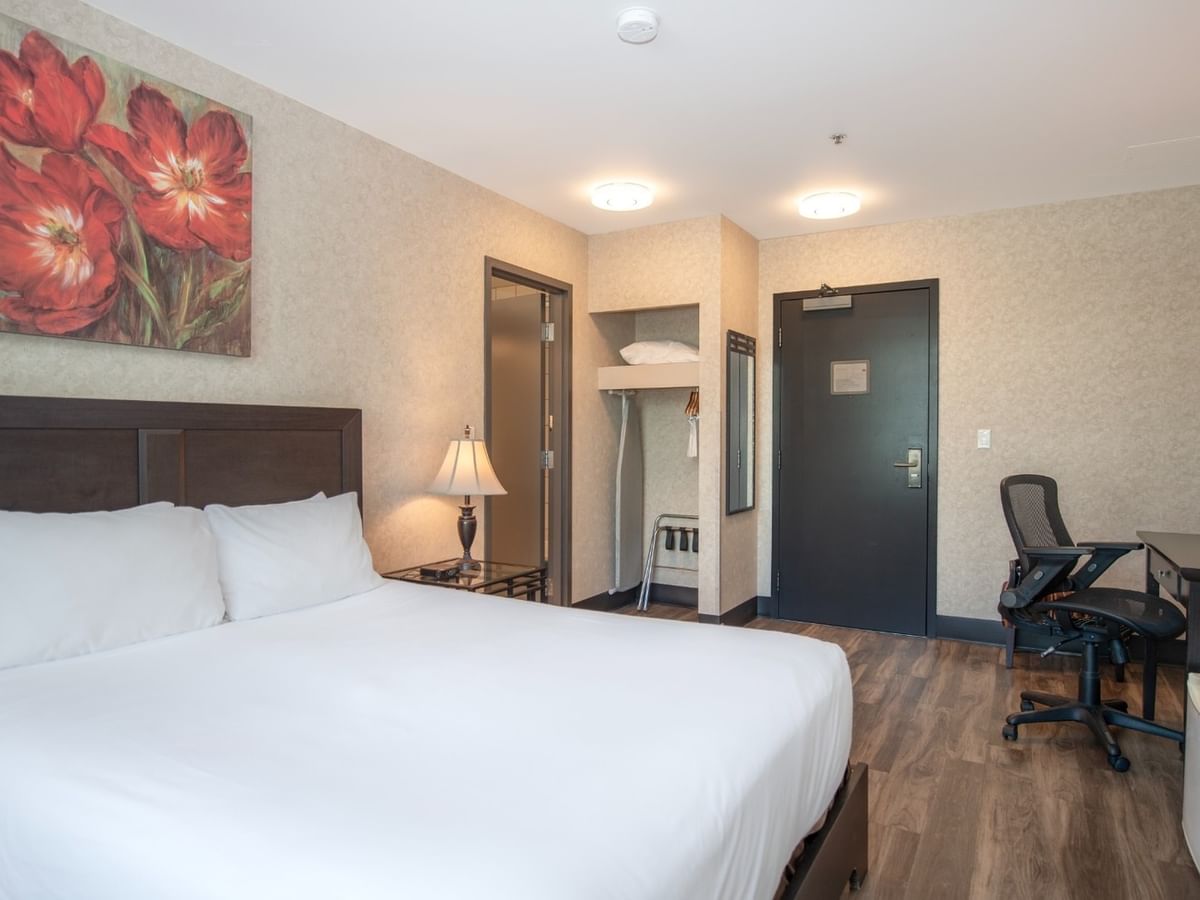 Coast Queen room with a large bed, desk, chair, and artwork on the wall at Coast Lonsdale Quay Hotel