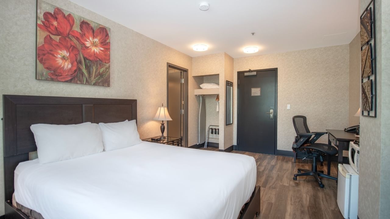 Coast Queen room with a large bed, desk, chair, and artwork on the wall at Coast Lonsdale Quay Hotel