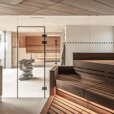 adults only spa interior with a sauna, wooden benches, and a stacked stone fountain at Falkensteiner Family Resort Lido