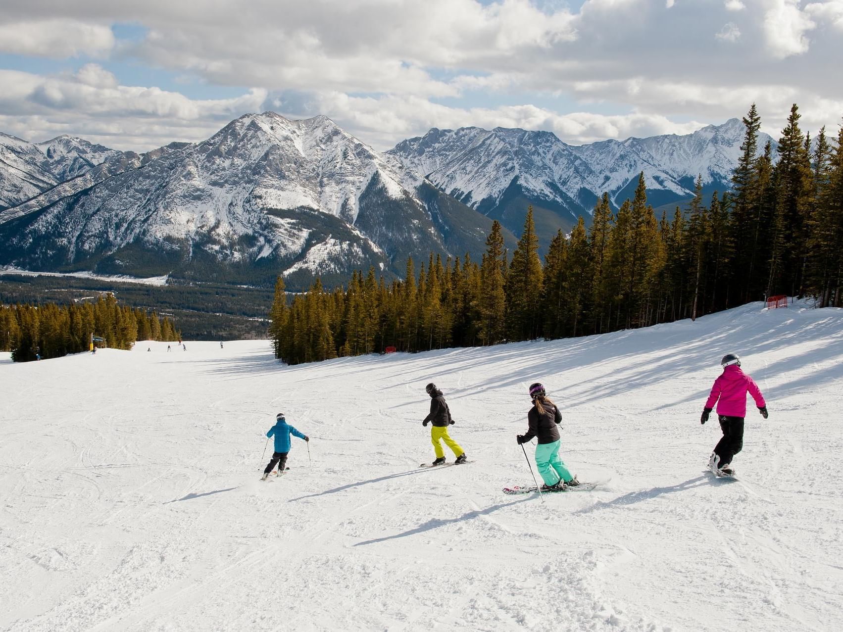 Skiers descending a snowy slope near Spring Creek Vacations, showcasing what to do in Canmore Alberta