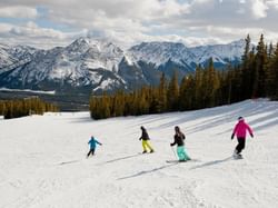 Skiers descending a snowy slope near Spring Creek Vacations, showcasing what to do in Canmore Alberta