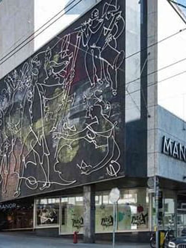 Modern mural by the Manor sign under a clear sky on a glass and stone building facade near Warwick Hotels & Resorts