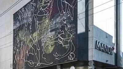 Modern mural by the Manor sign under a clear sky on a glass and stone building facade near Warwick Hotels & Resorts