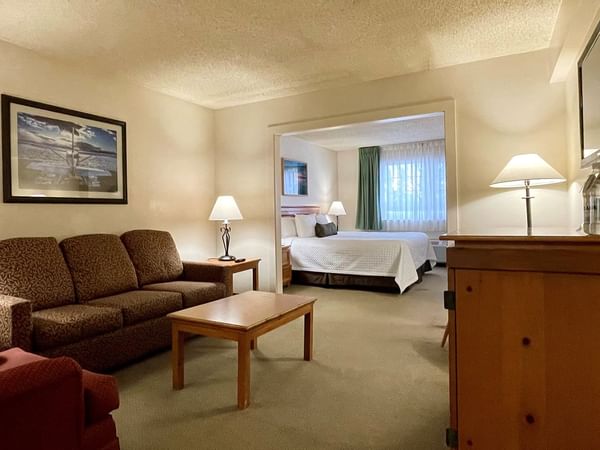 Sofa and coffee table and a bed in separate room with a window