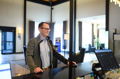 Staff member standing by a dark check-in counter under soft ceiling lights in a lobby at Rodd Miramichi River