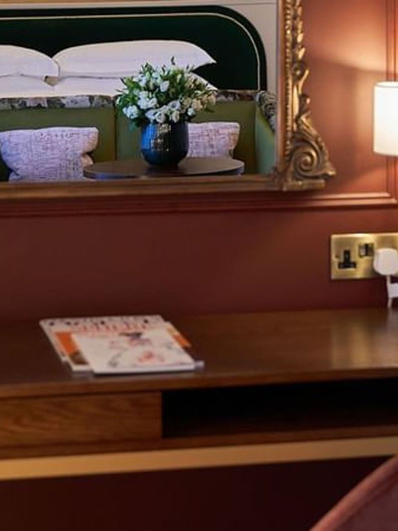 Reflective mirror, desk with lamp, and magazines in a Deluxe Room at The Capital Hotel, Apartments & Townhouse 