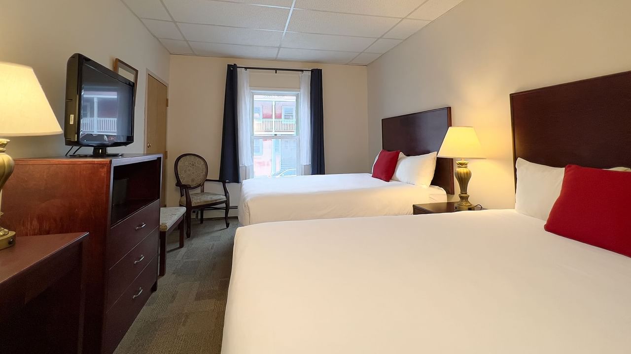 Hotel bedroom with two queen beds, tv, chair, mirror, and lamp