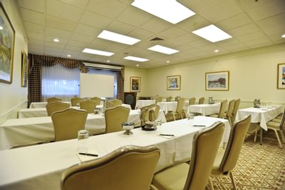 Classroom setup with tables and chairs arranged toward a projector screen at Farmington Inn and Suites