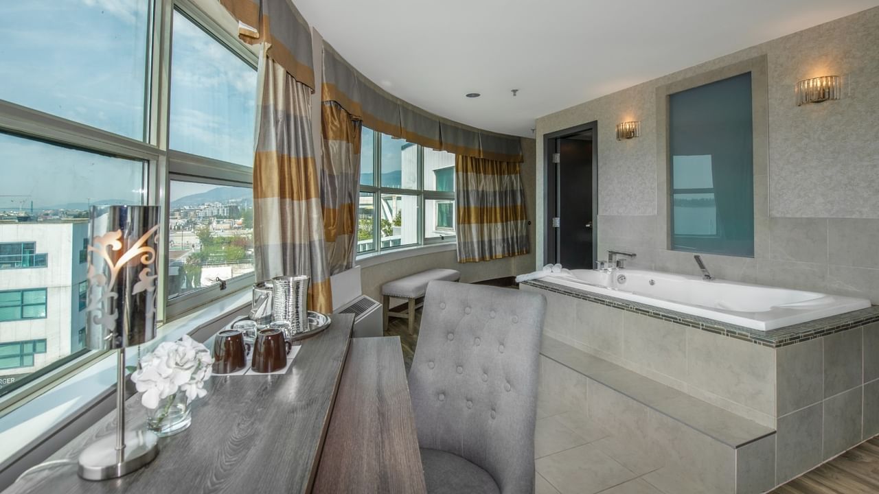 Coast Carrie Cates Penthouse Suite 
with a large bathtub and a window with a city view at Coast Lonsdale Quay Hotel