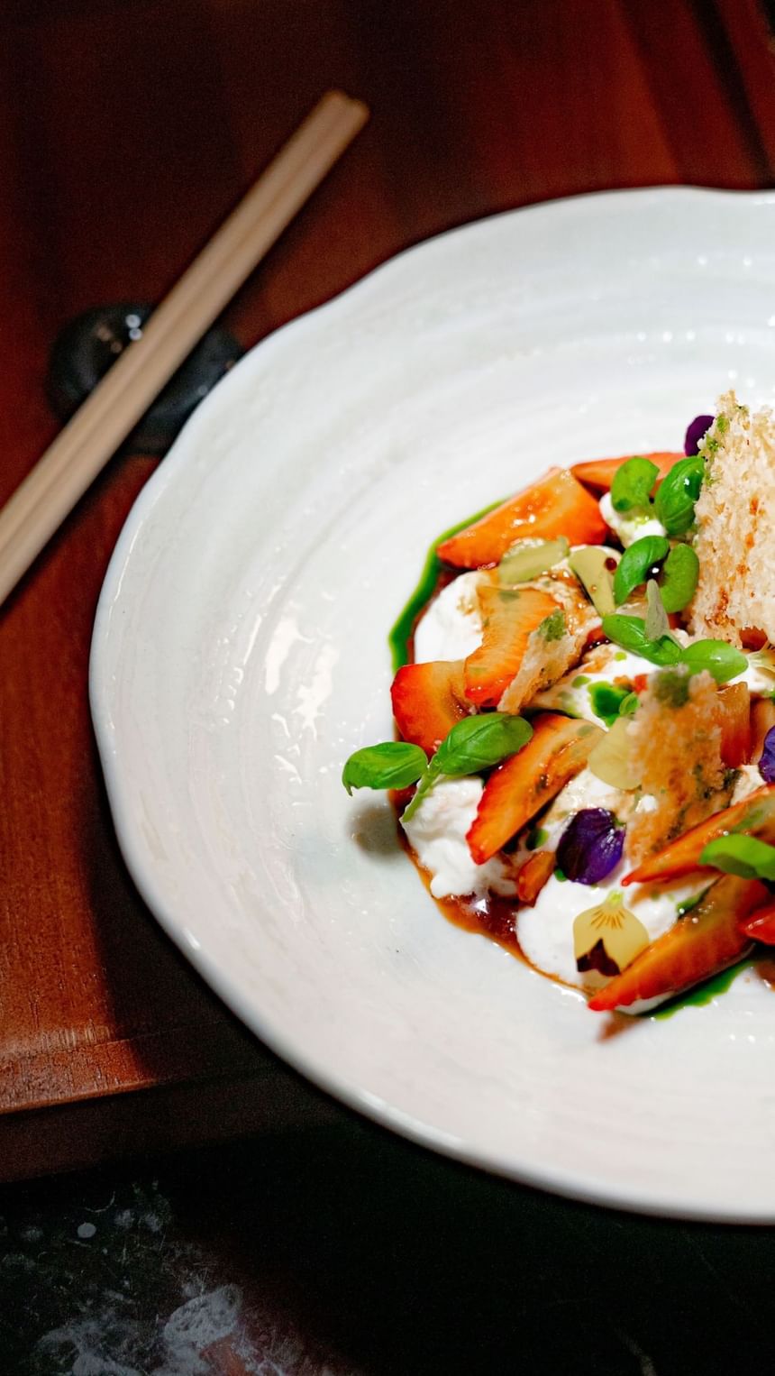 A vibrant dish featuring sliced fruit, herbs, and creamy texture served in a bowl at The Kitchens