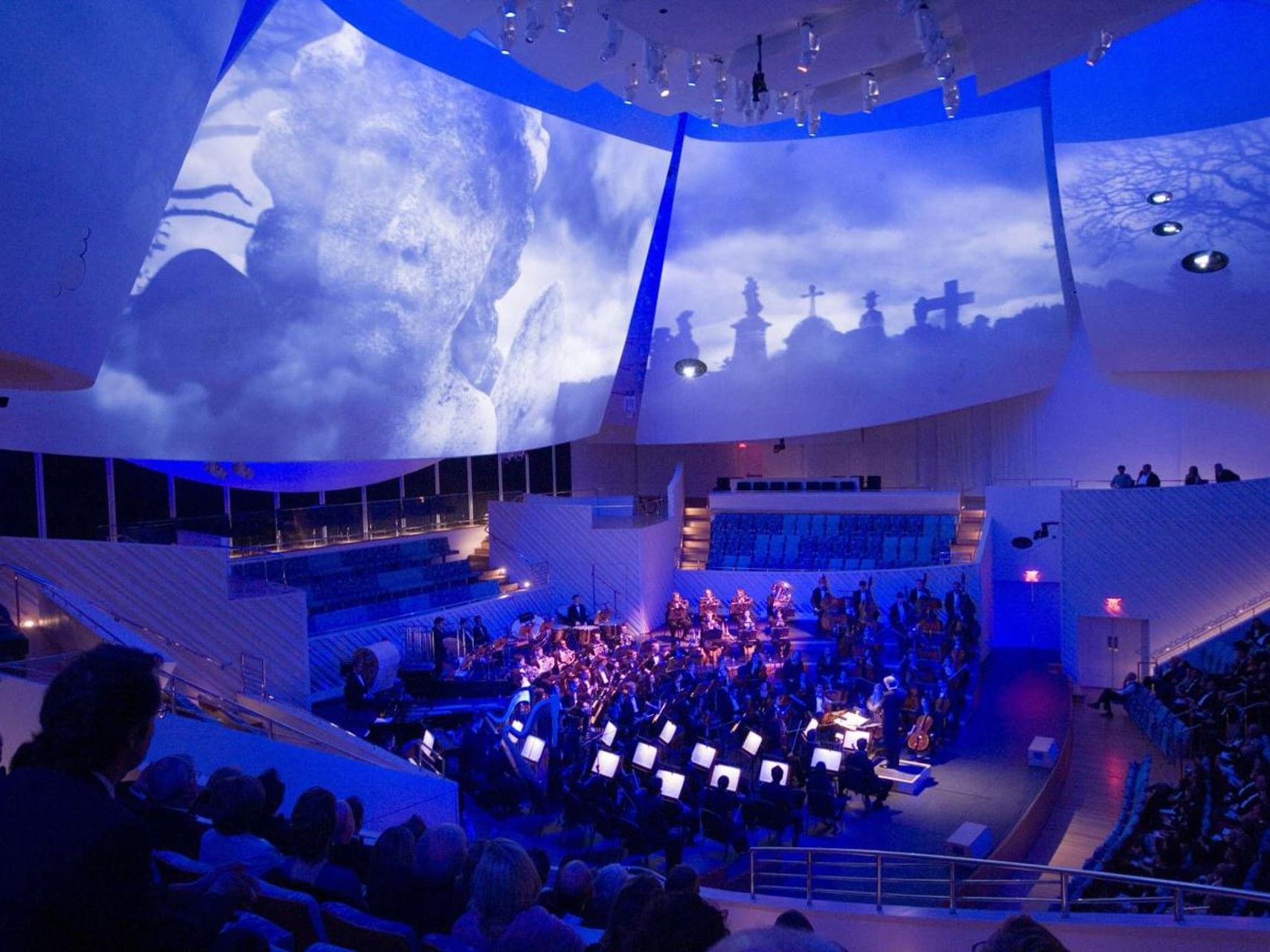 Grand orchestra performance at New World Center near Riviera Hotel South Beach with blue lighting and large projections