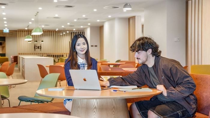 Two residents working together on a laptop at UniLodge Brisbane City study spaces.