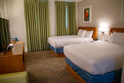 Two queen beds with white linens and a view of the windows in Deluxe Double Queen Oasis at Centennial Plaza Resort