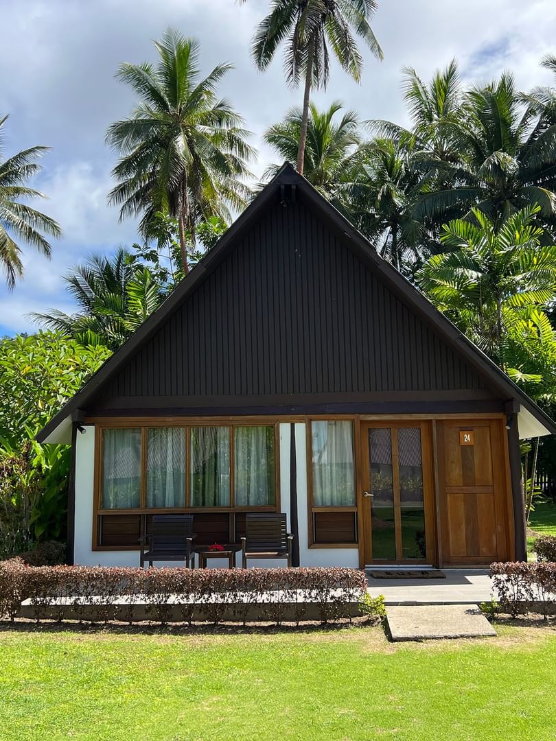 Small wooden Garden View Bure with lush green surroundings at Tambua Sands Beach Resort in Sigatoka