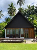 Small wooden Garden View Bure with lush green surroundings at Tambua Sands Beach Resort in Sigatoka