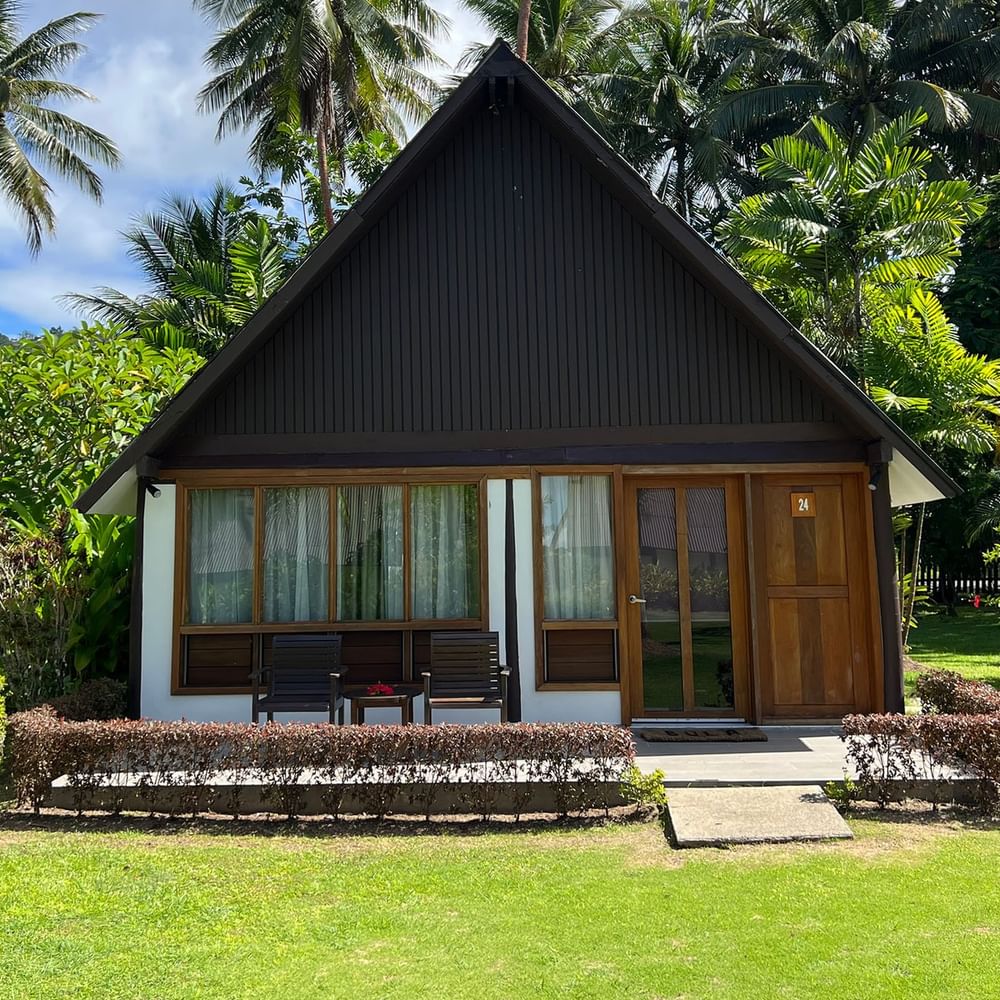 Small wooden Garden View Bure with lush green surroundings at Tambua Sands Beach Resort in Sigatoka.