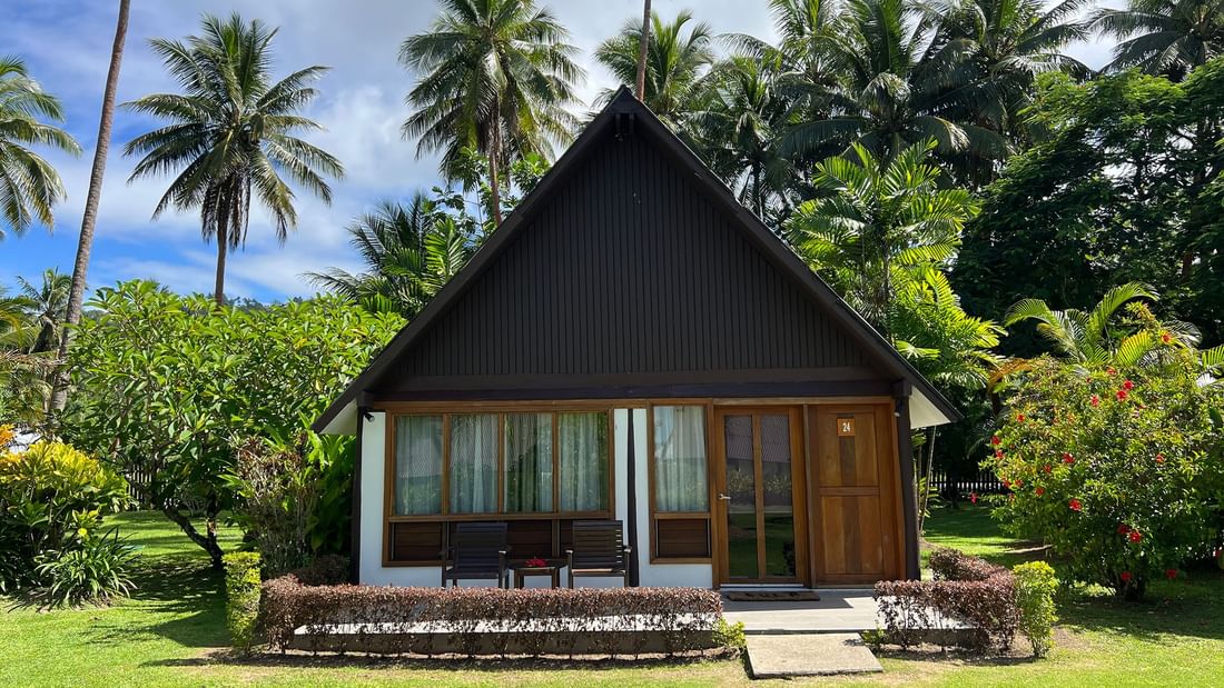 Small wooden Garden View Bure with lush green surroundings at Tambua Sands Beach Resort in Sigatoka