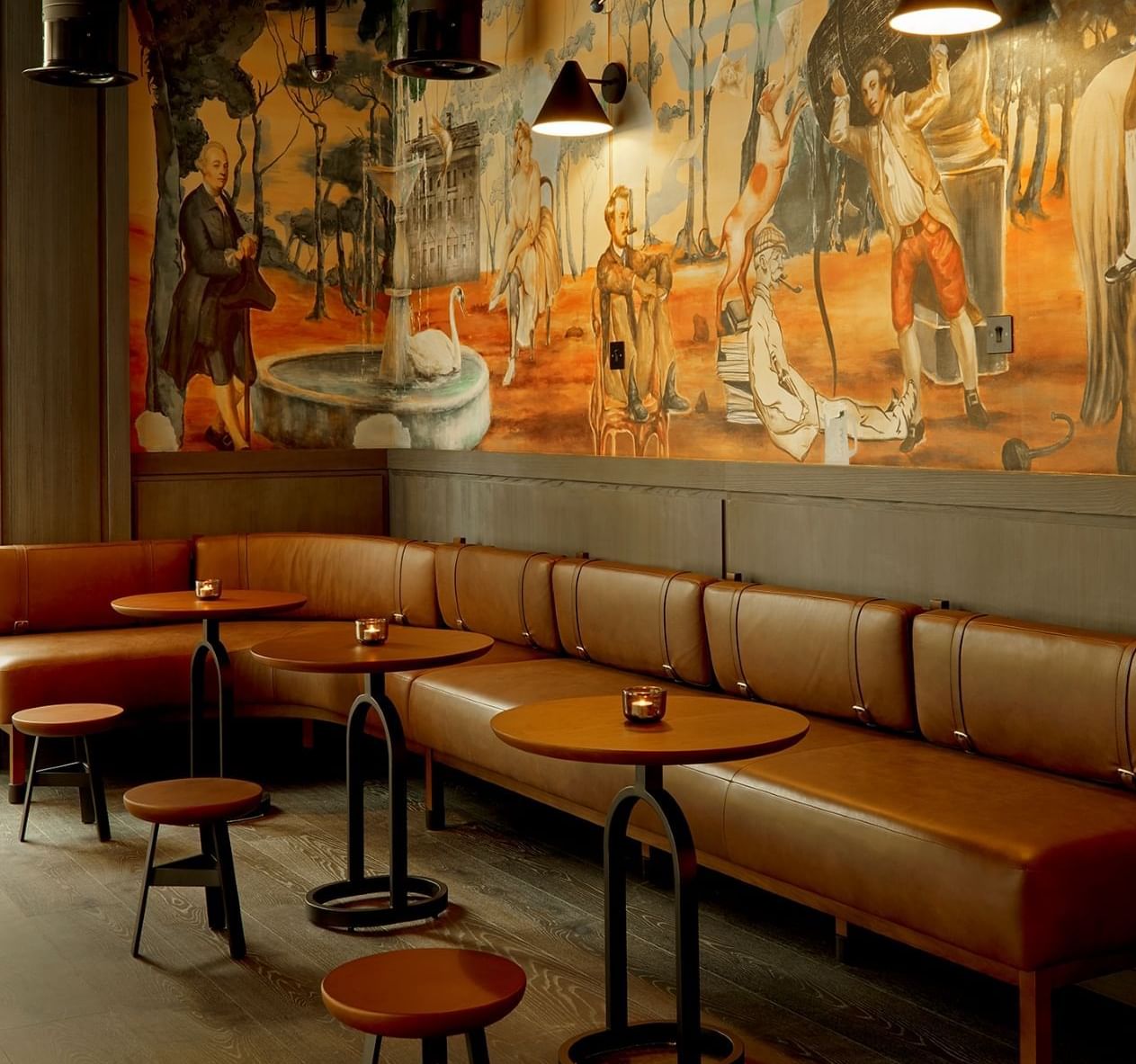 Stylish interior of Joshua’s Tavern at The Londoner, featuring leather seating and a grand historical mural on the wall