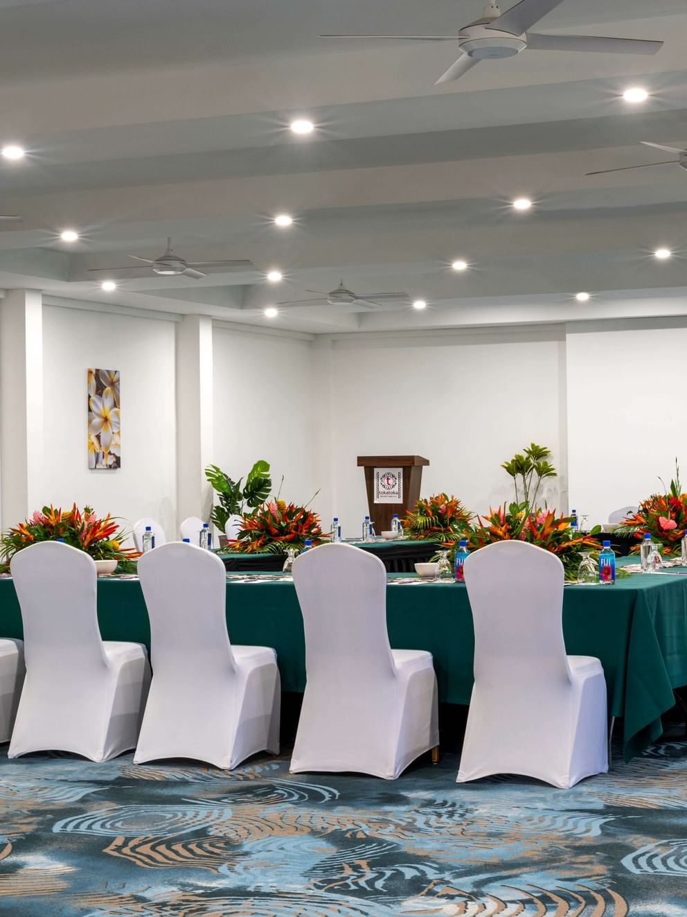 Table with green cloths and floral centerpieces by white chairs in Conference Room 1 at TokaToka Resort Nadi Fiji