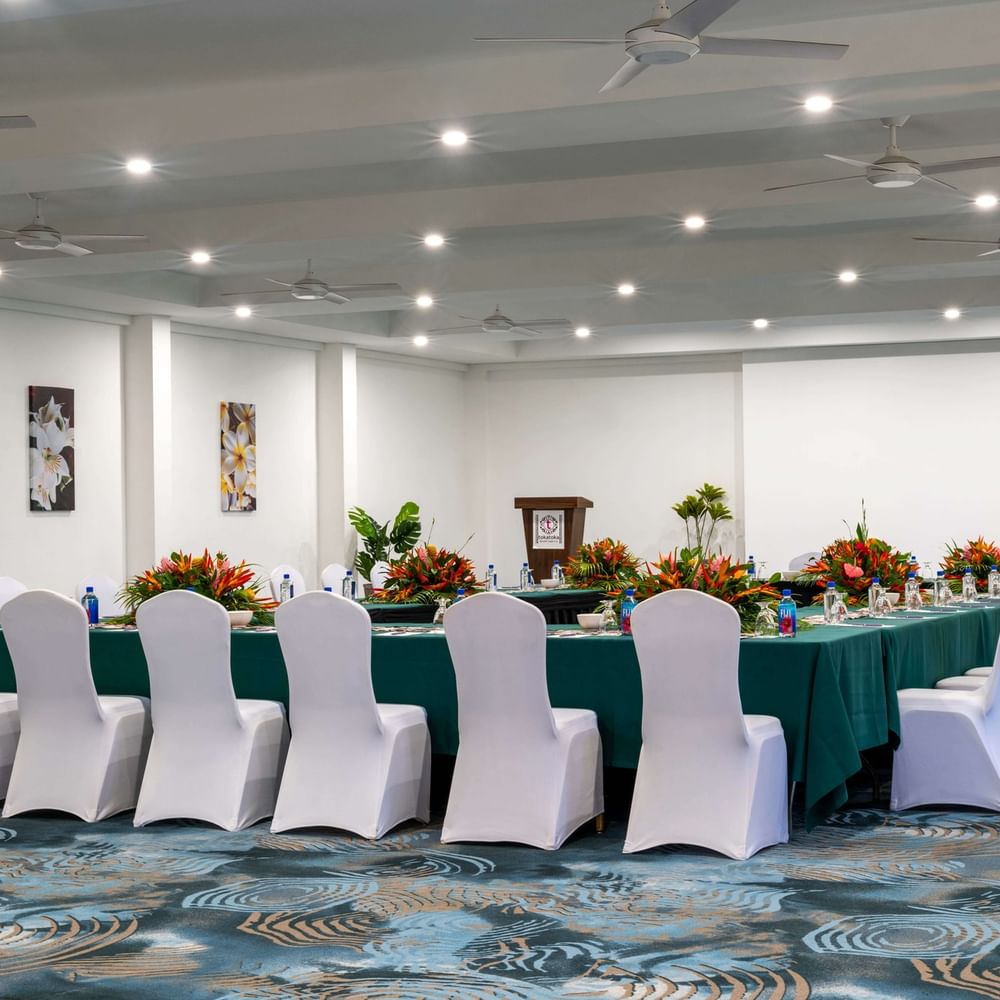 Table with green cloths and floral centerpieces by white chairs in Conference Room 1 at TokaToka Resort Nadi Fiji