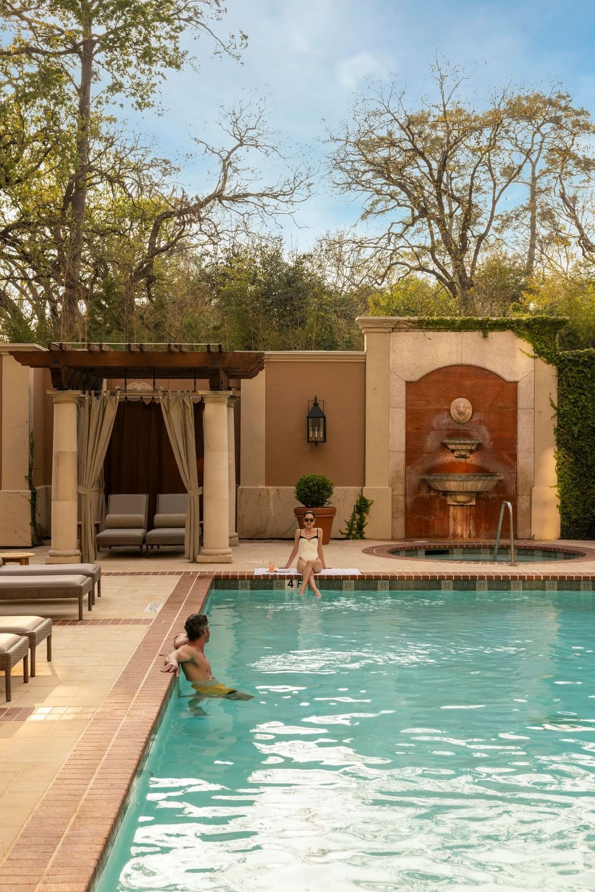 Serene poolside scene at Granduca Houston, one of the top Houston luxury hotels, with lounge chairs and a fountain wall