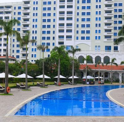 Large pool nestled amidst lush palm trees at Hanoi Daewoo Hotel