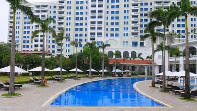 Large pool nestled amidst lush palm trees at Hanoi Daewoo Hotel