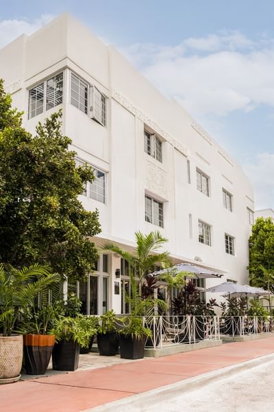 Exterior of Riviera Hotel South Beach showcasing white Art Deco architecture and lush landscaping under a clear blue sky