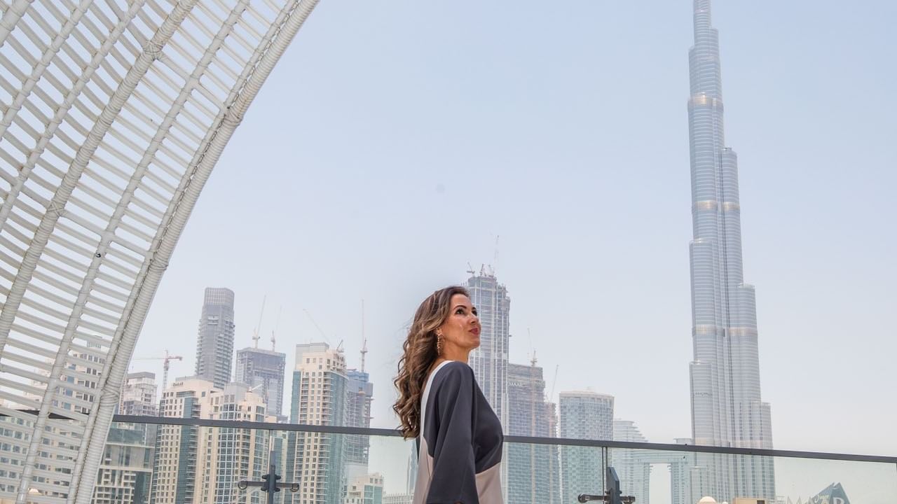 A lady posing for a picture on a balcony with a view of the Burj Khalifa at DAMAC Maison Distinction