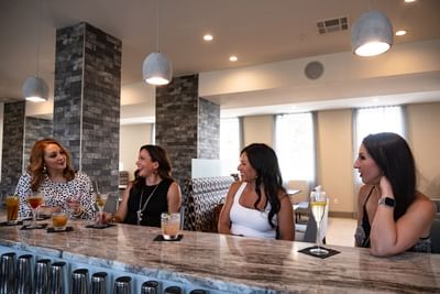 Four friends enjoying cocktails and a lively conversation at the Grand Centennial Wine Bar inside Centennial Plaza Resort