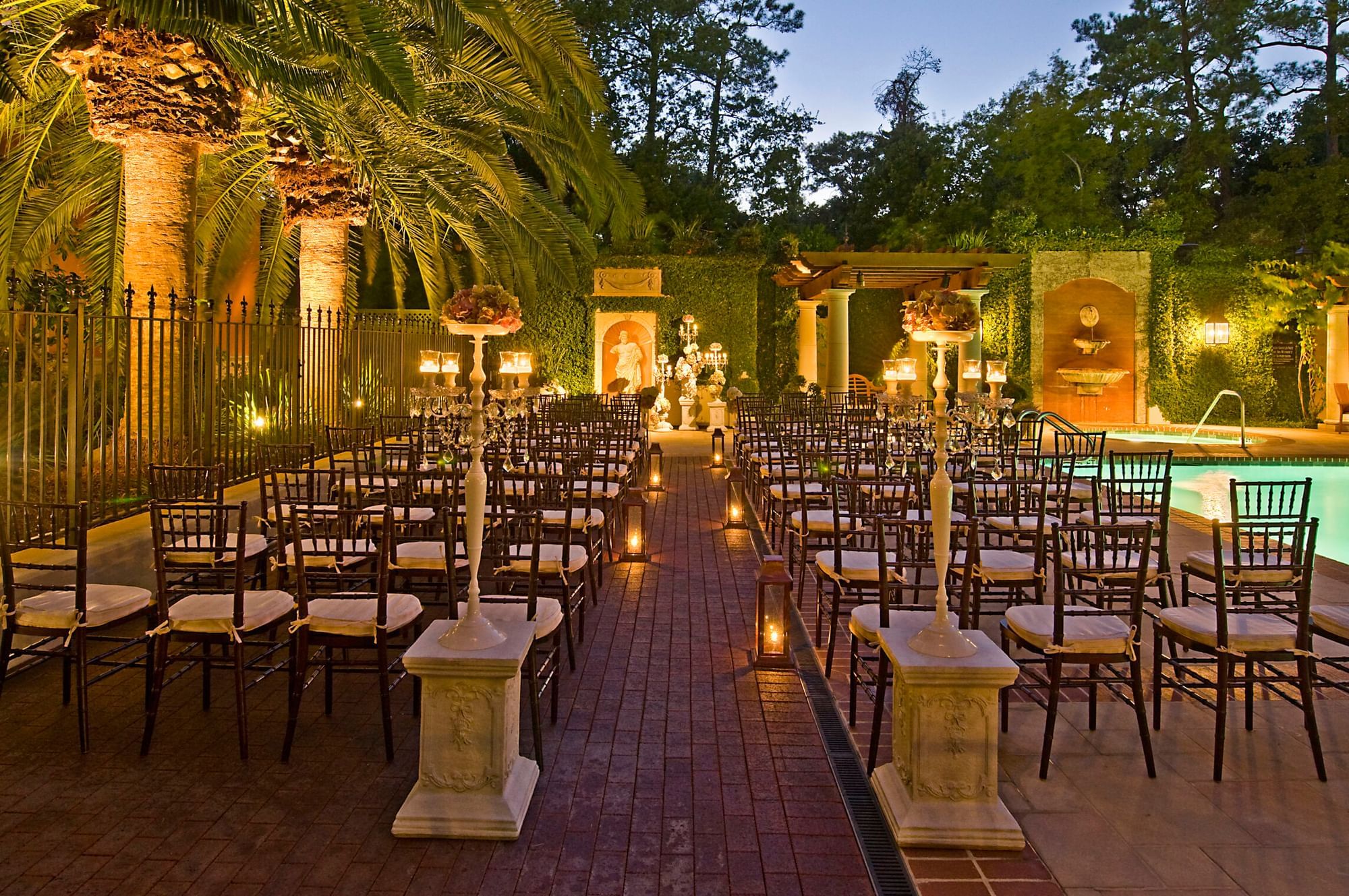 Elegant outdoor wedding seating with lit candles by the pool at Granduca Houston, a premier Houston wedding venue