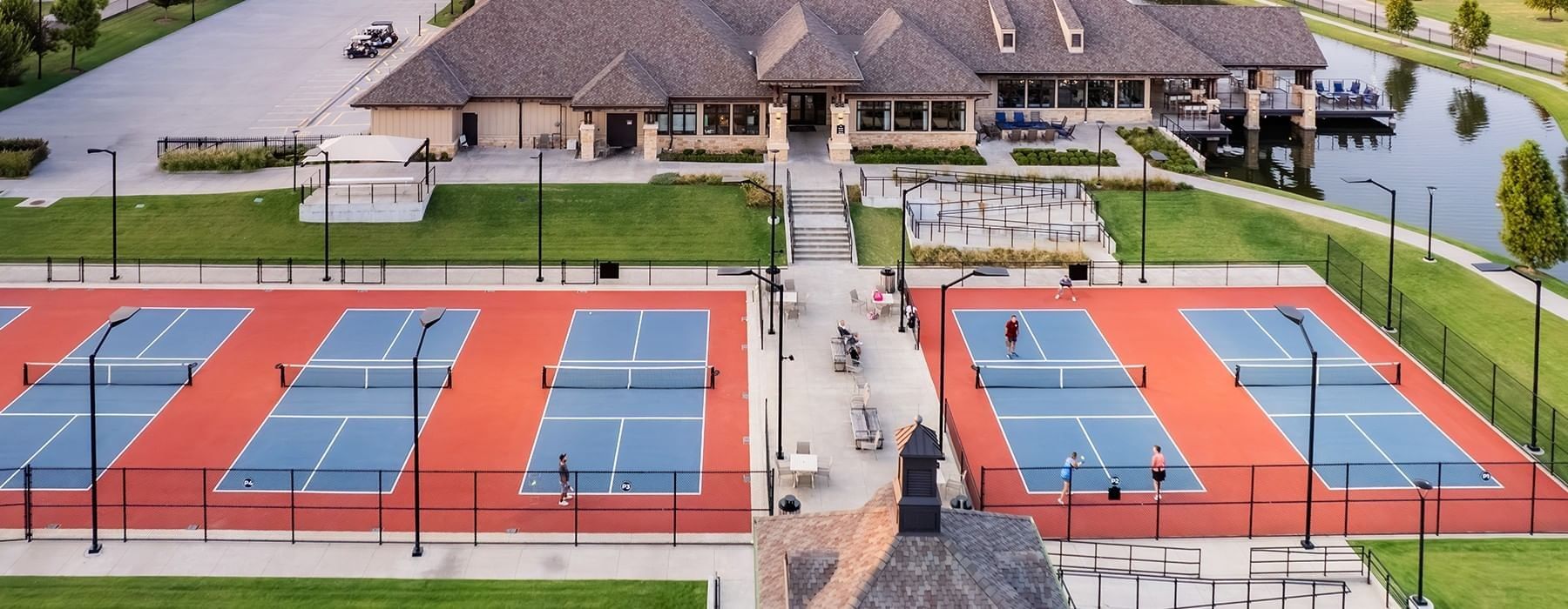 Top-down view of blue and red pickleball courts next to a large resort clubhouse at Shangri-La Resort and Golf Club