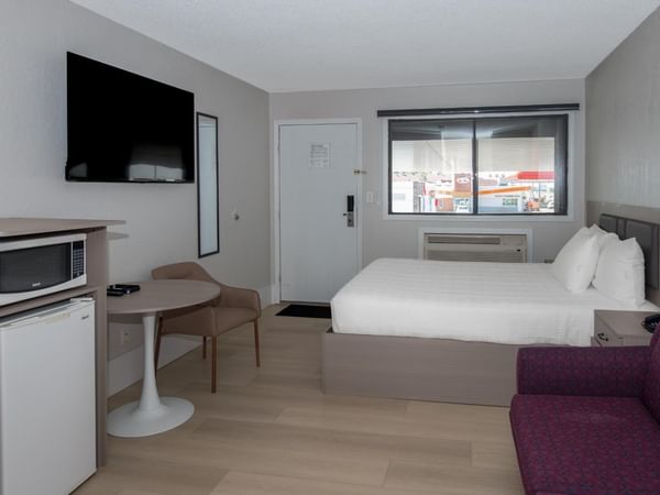 Guest room at Coast Red Deer Hotel with a queen bed, desk, TV and seating