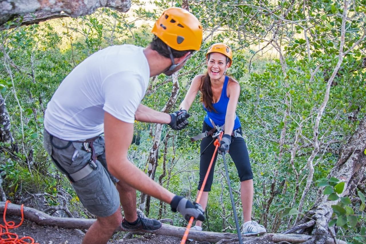 Rock climbing using harnesses, cords & safety helmets near Fiesta Americana Travelty