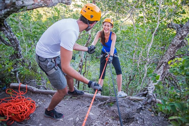 Rock climbing using harnesses, cords & safety helmets near Fiesta Americana Travelty
