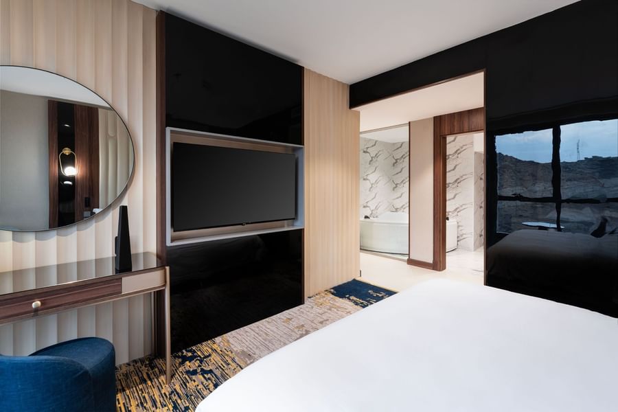 TV and work desk facing the bed by the doorway to the bathroom in Royal Suite at Warwick Al Taif Hotel