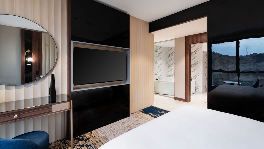 TV and work desk facing the bed by the doorway to the bathroom in Royal Suite at Warwick Al Taif Hotel