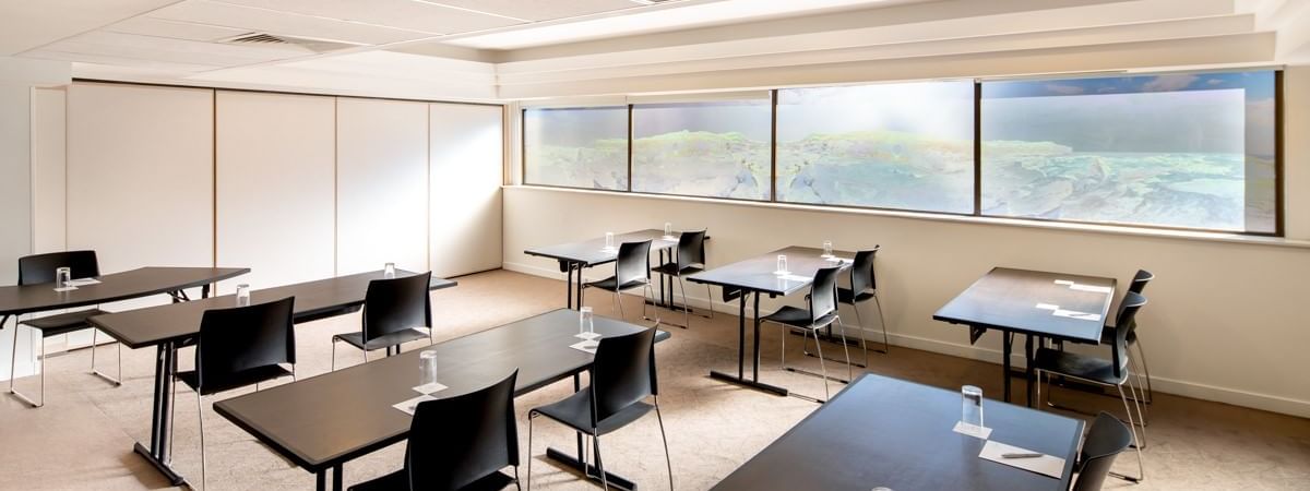 Classroom table setup by the large windows in Banksia at Novotel Sydney International Airport