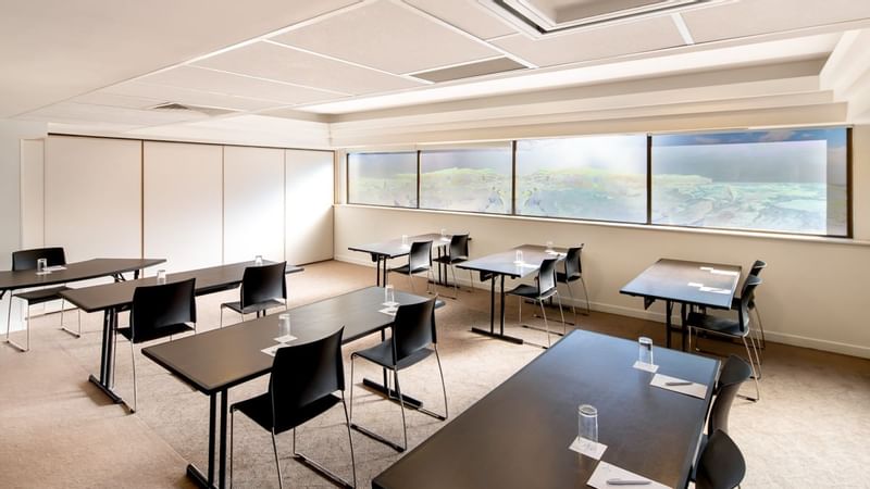 Classroom table setup by the large windows in Banksia at Novotel Sydney International Airport