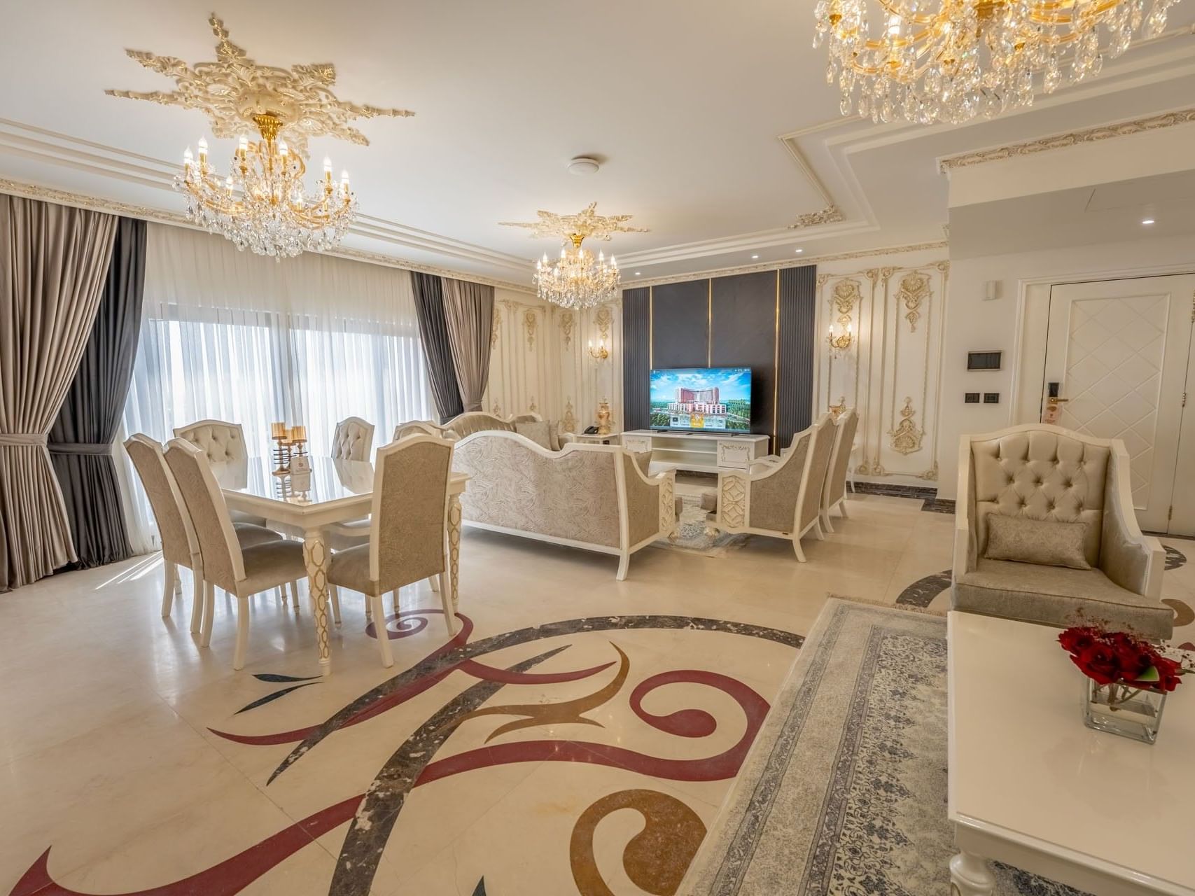 Elegant living room with chandeliers, dining set, and couch at World Heart Hotel Baghdad.