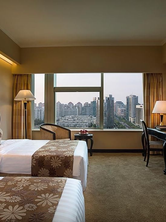 TV facing beds with a couch by the window in Standard Room at Celebrity International Grand Hotel