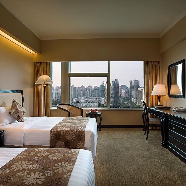 TV facing beds with a couch by the window in Standard Room at Celebrity International Grand Hotel