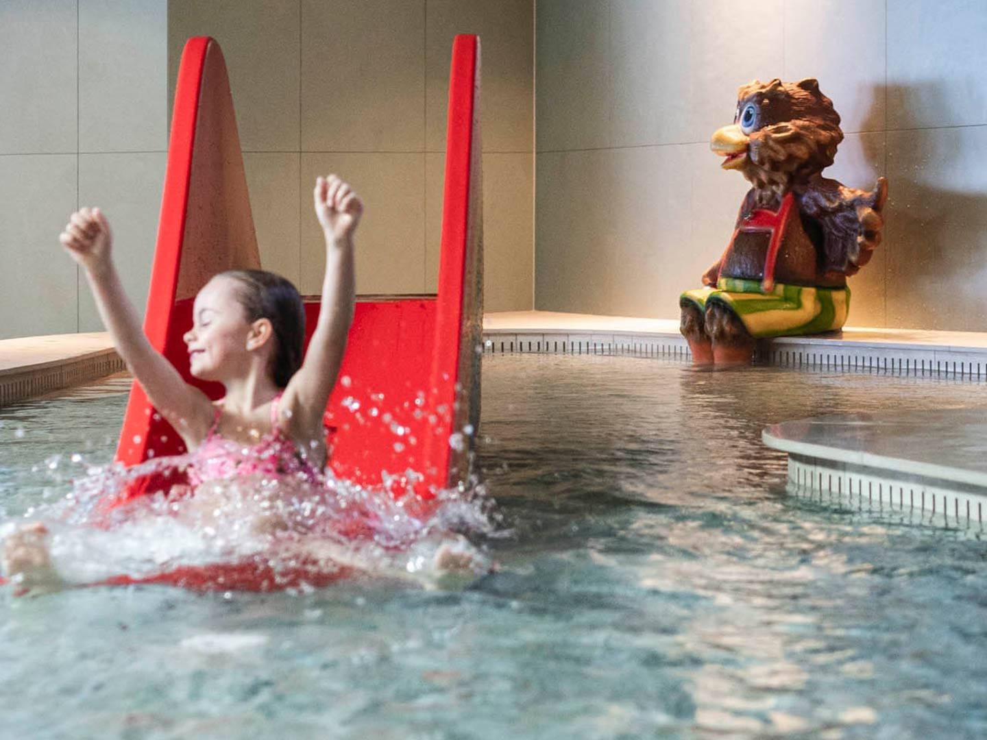kid enjoying a water slide in a pool, Falkensteiner Hotels