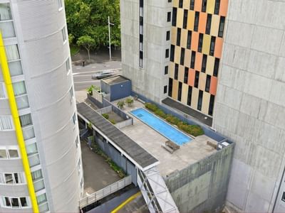 Aerial view of a modern hotel with rooftop pool and surrounding buildings.