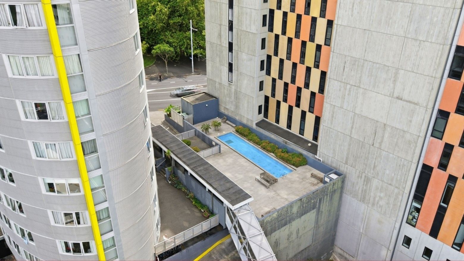 Aerial view of a modern hotel with rooftop pool and surrounding buildings.