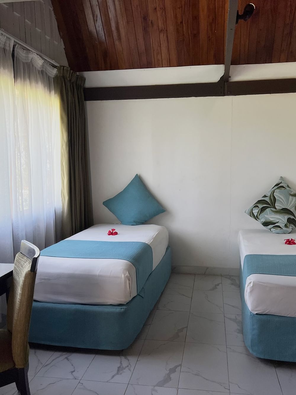 Garden View Bure interior with two beds and window at Tambua Sands Beach Resort in Sigatoka.
