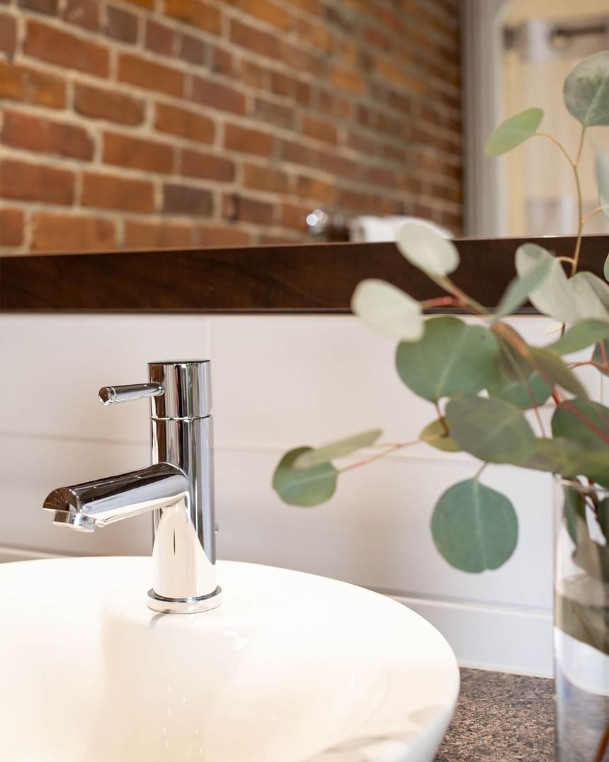 a close up of a stainless steel sink with a vase of greenery bes