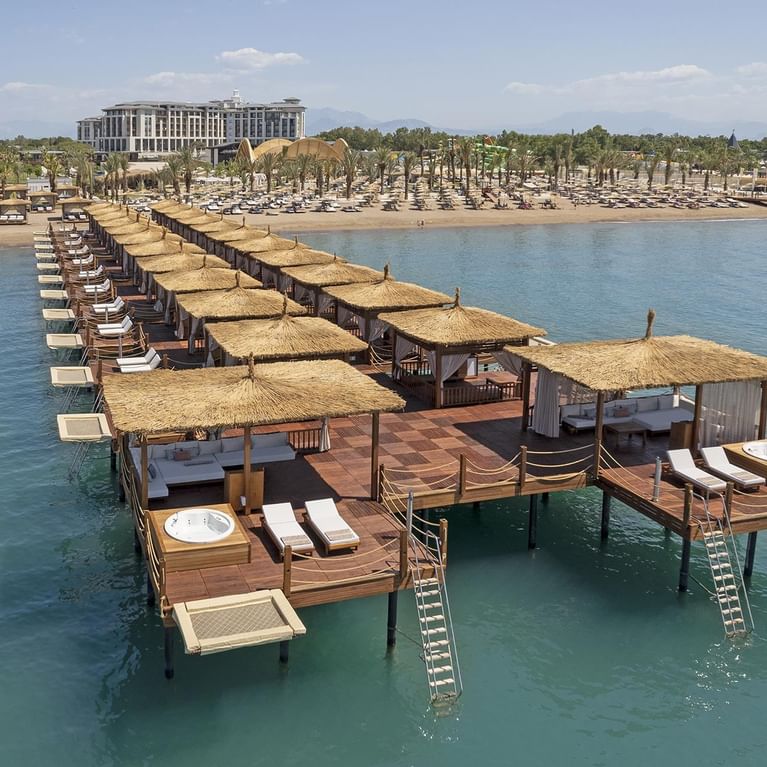 Набережная с рядами лежаков и домиками для отдыха на воде в отеле Cullinan Belek в Анталии.