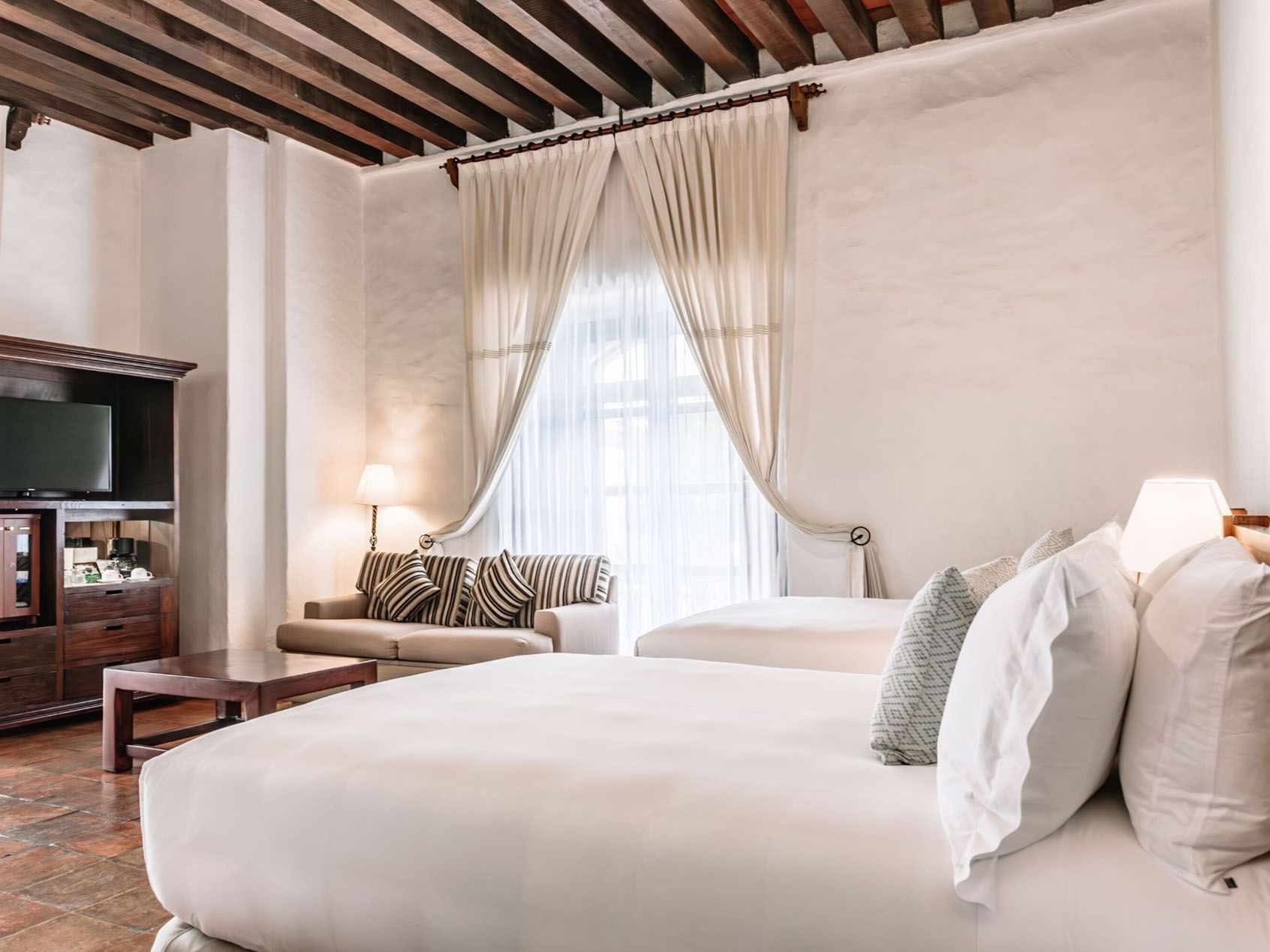 TV lounge area with plush seating by the bed in 2 Double Grand Class Suite at Quinta Real Oaxaca