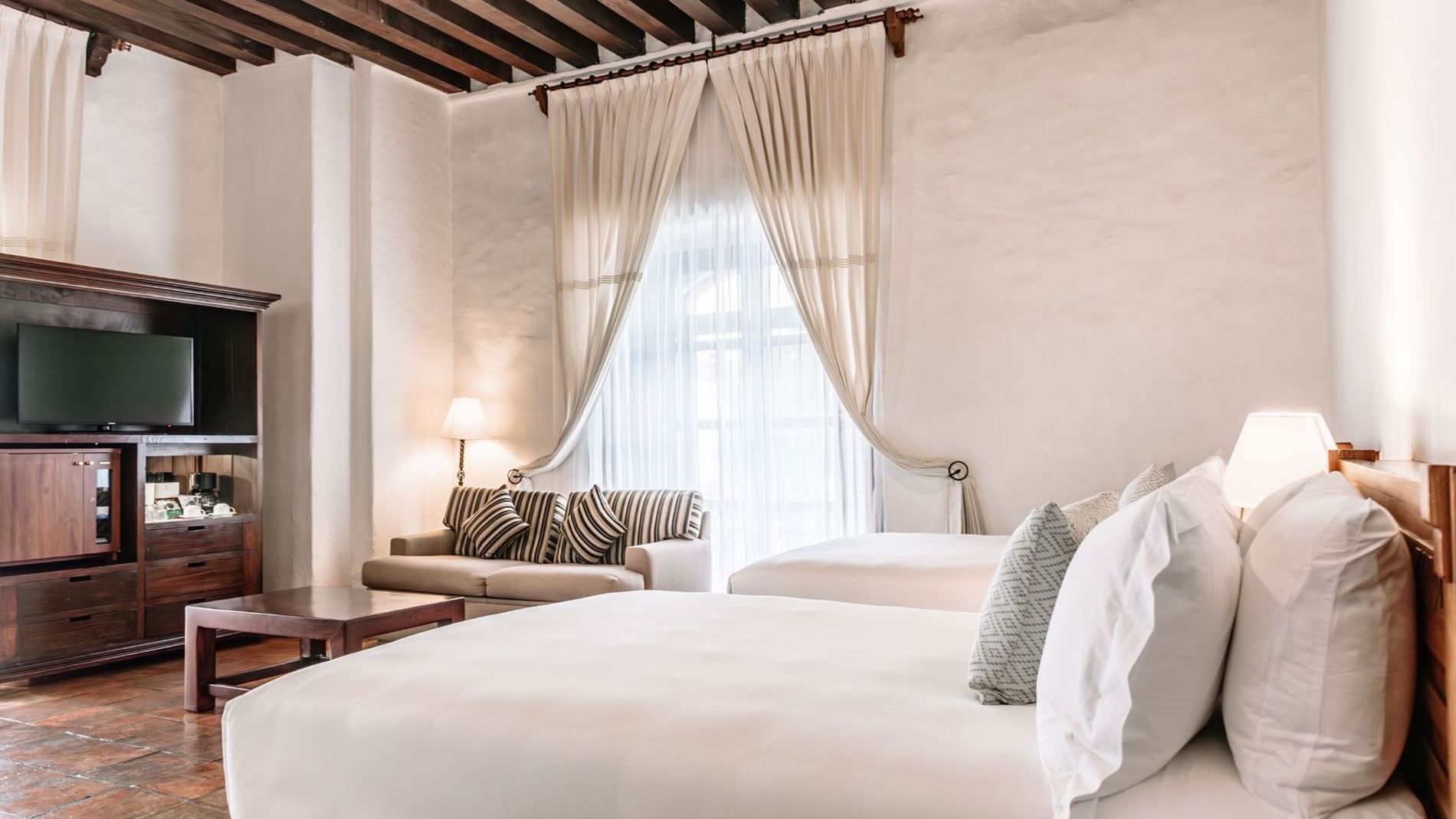 TV lounge area with plush seating by the bed in 2 Double Grand Class Suite at Quinta Real Oaxaca